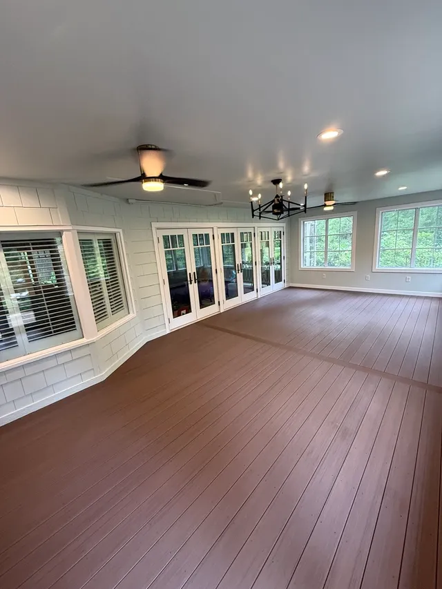 Sunroom interior with composite flooring, French doors, and ceiling fans