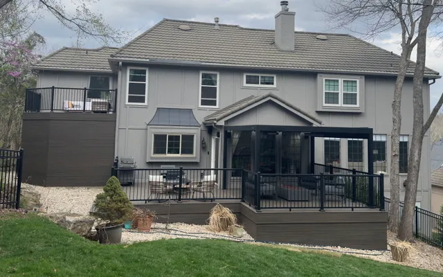 Multi-level composite deck with black railing and louvered pergola