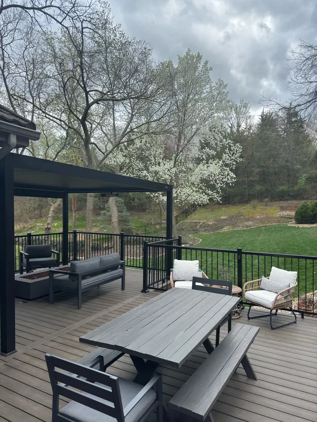 Composite deck with louvered pergola, outdoor dining area, and black metal railing