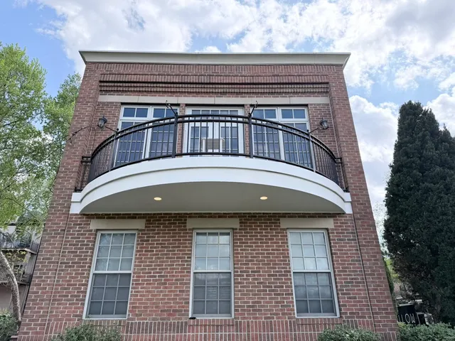 Curved balcony deck with black metal railing on brick home